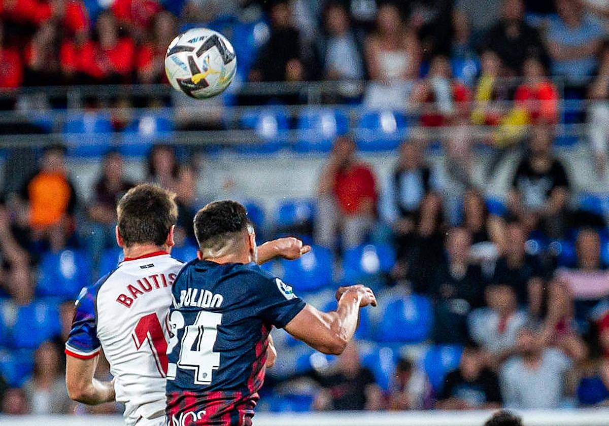 Jon Bautista salta por un balón ante el defensor del Huesca.