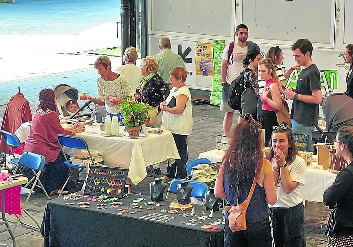 Jokin Eizmendi durante la exhibición de levantamiento de piedra. A la derecha, el mercado de creadores.