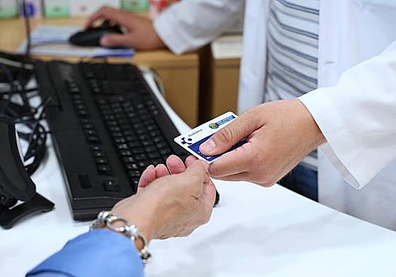 Un farmaceútico se dispone a leer la tarjeta sanitaria de una paciente en una botica de Errenteria.