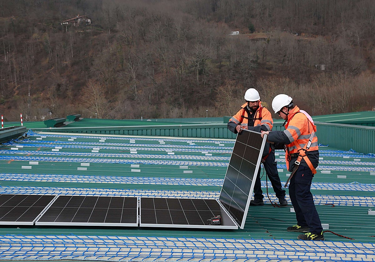 Dos operarios instalan placas solares en el techo de un pabellón en Bera de Bidasoa.