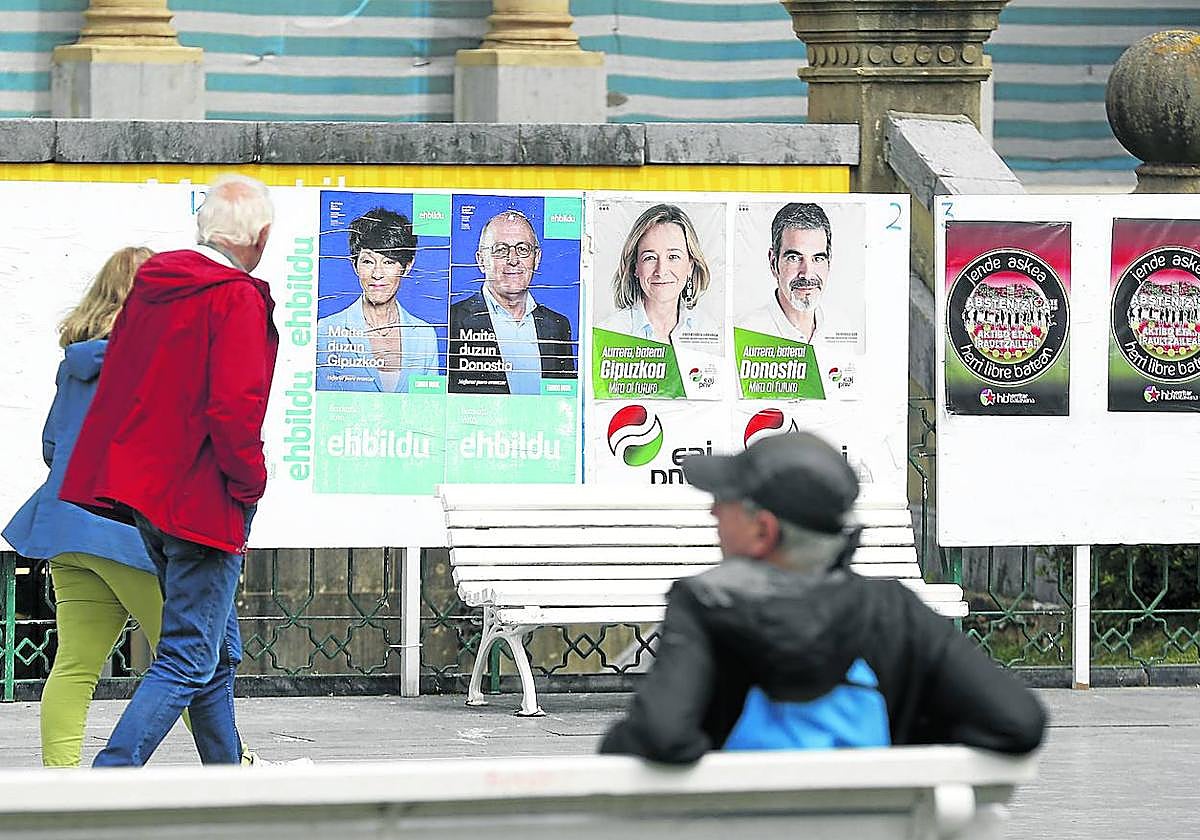 Una pareja pasa por delante de unos carteles electorales en Alderdi Eder, en San Sebastián.