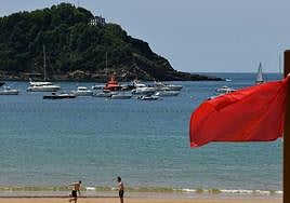 La bandera roja colocada este lunes, con el operativo de reflote del yate de fondo.