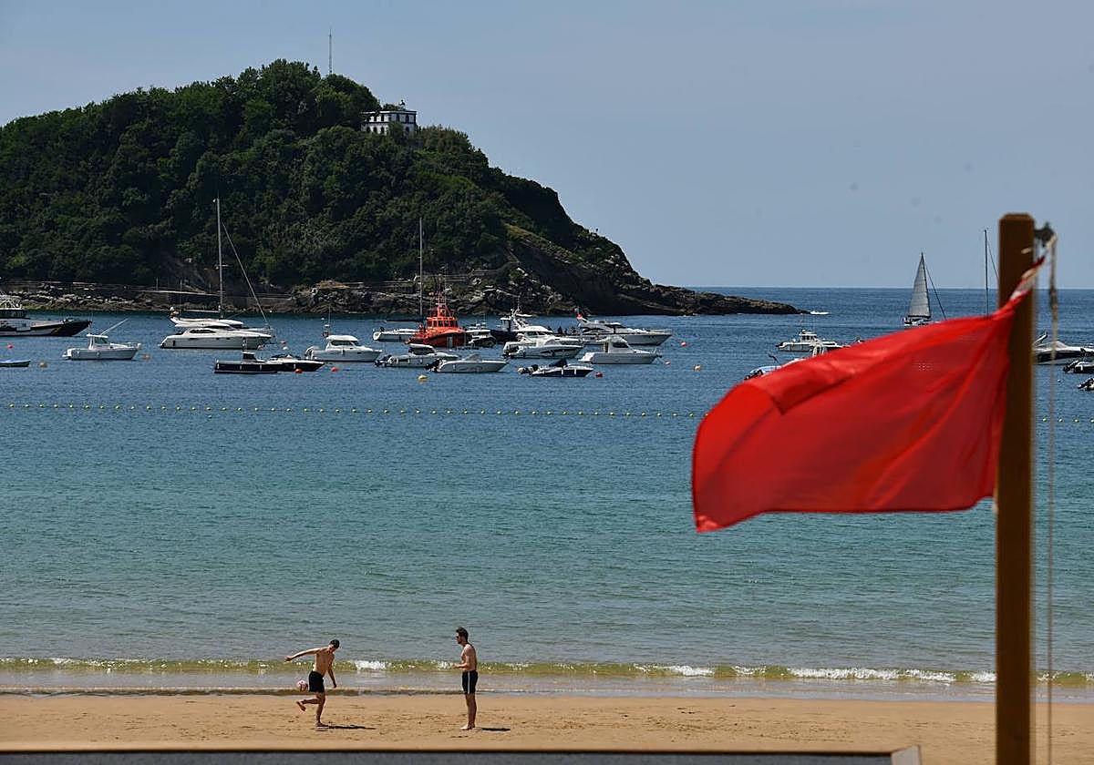 La bandera roja colocada este lunes, con el operativo de reflote del yate de fondo.