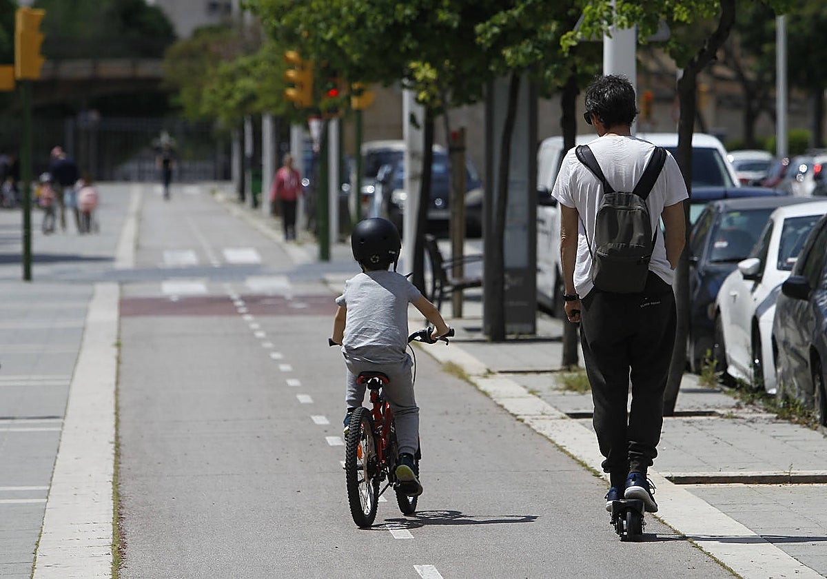 Un menor pasea con su padre en bicicleta.