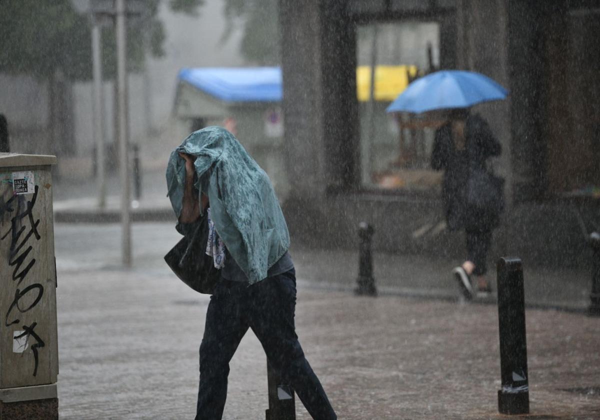 Una mujer se cubre la cabeza tras verse sorprendida por una violenta tormenta ayer en Zumaia