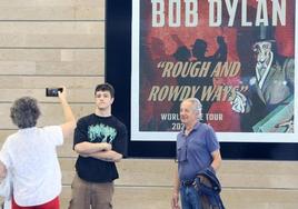 Unos fans de Dylan se fotografían con el cartel del concierto detrás.