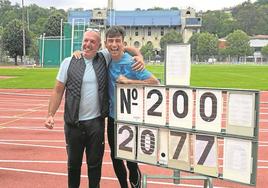 El joven Andoni Calbano, acompañado por su entrenador Oskar Ezker, posa con el marcador que acredita su récord.