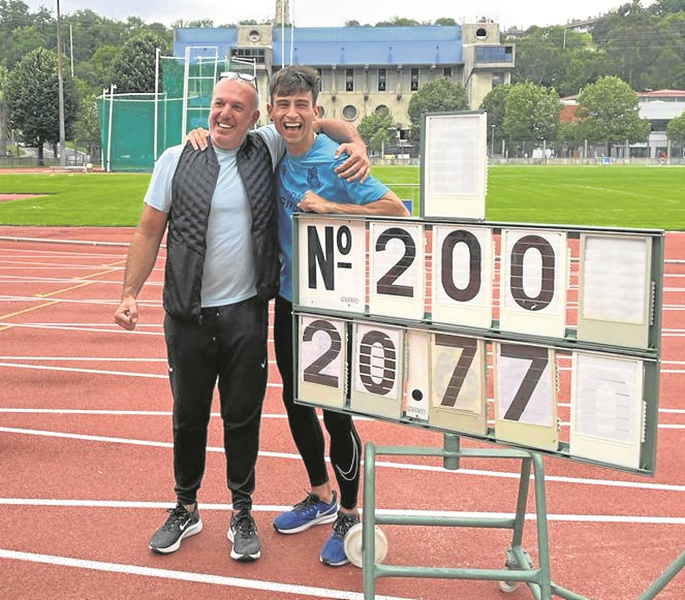 El joven Andoni Calbano, acompañado por su entrenador Oskar Ezker, posa con el marcador que acredita su récord.
