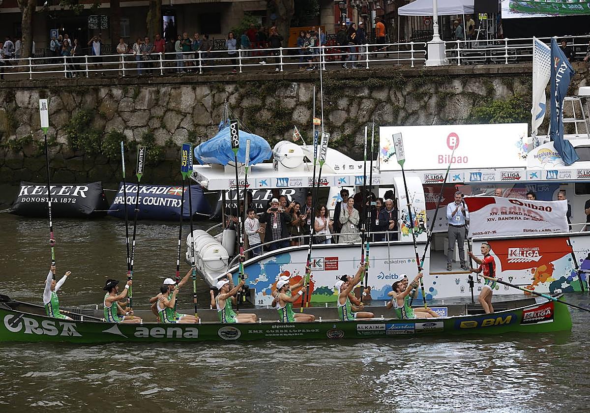 Amunarriz ondea la Bandera de Bilbao mientras sus remeros levantan los remos.