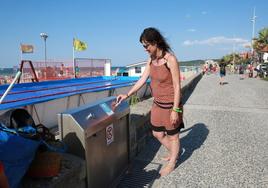 Una joven aplica el pulsador de un grifo en la playa de Hendaia, donde, un verano más, el Ayuntamiento no ha habilitado las duchas.