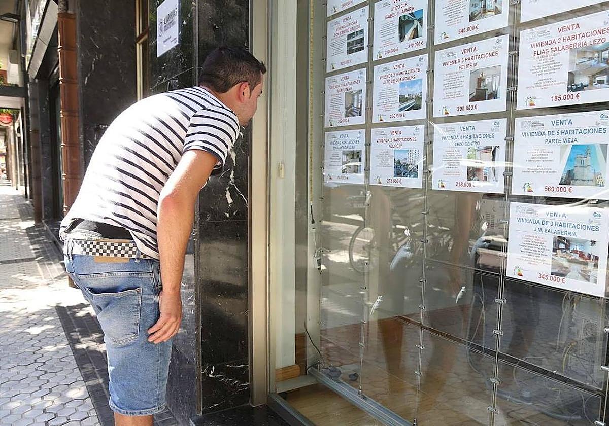 Un joven consulta el escaparate de una inmobiliaria.