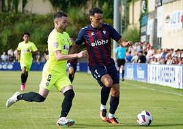 Quique conduce el balón perseguido por Hernando.