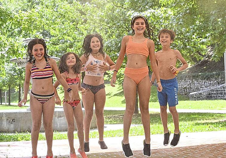 Unas niñas se refrescan bajo unos vaporizadores de agua instalados en Tolosa.