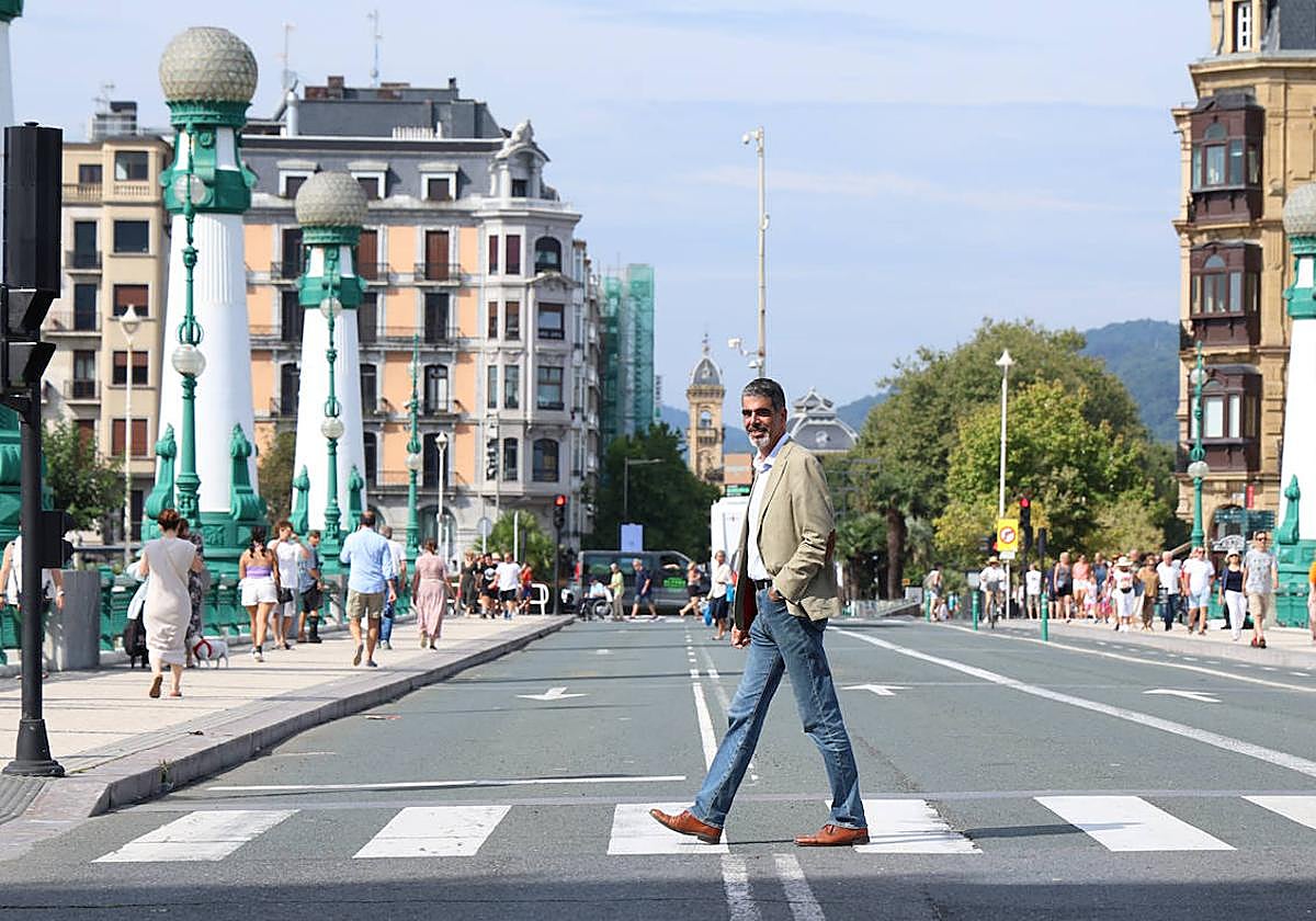 Eneko Goia cruza el paso de cebra del puente de Zurriola con el Ayuntamiento al fondo.