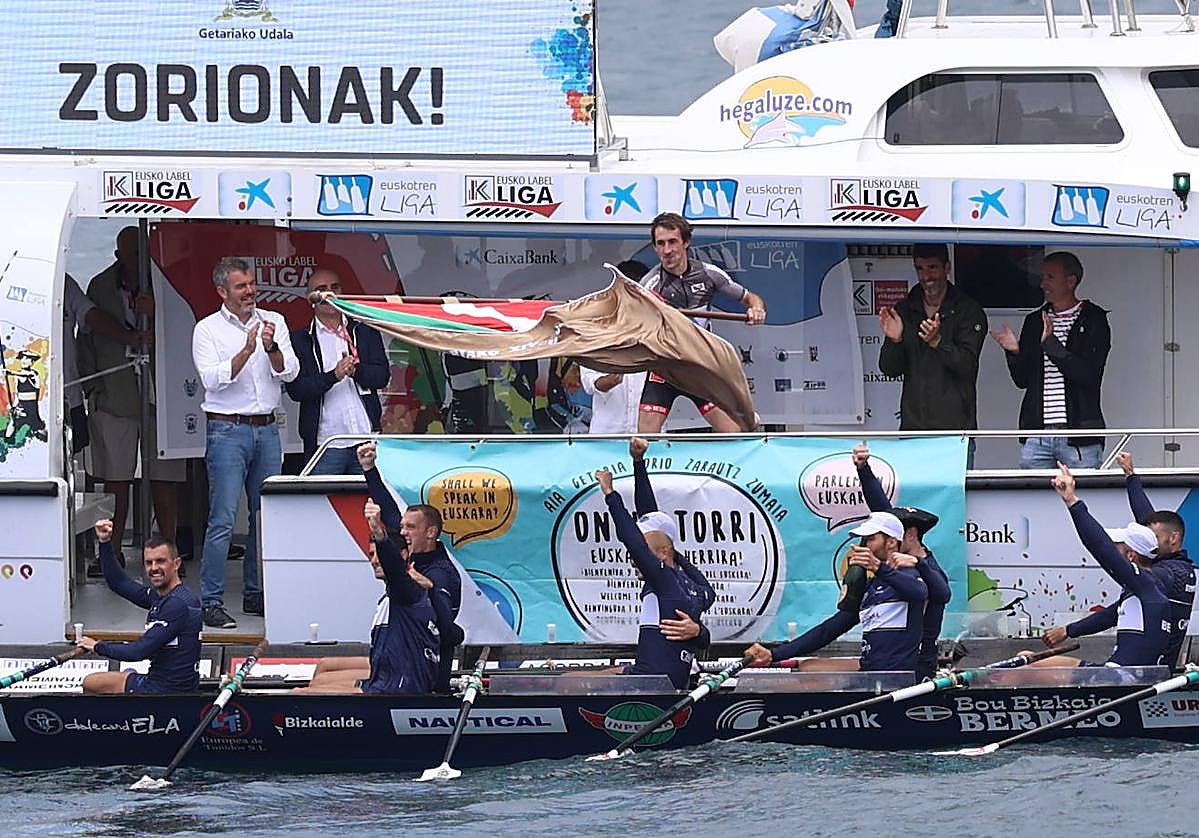 Gorka Aranberri ondea la Ikurriña de Getaria ante la alegría de los remeros de Urdaibai.