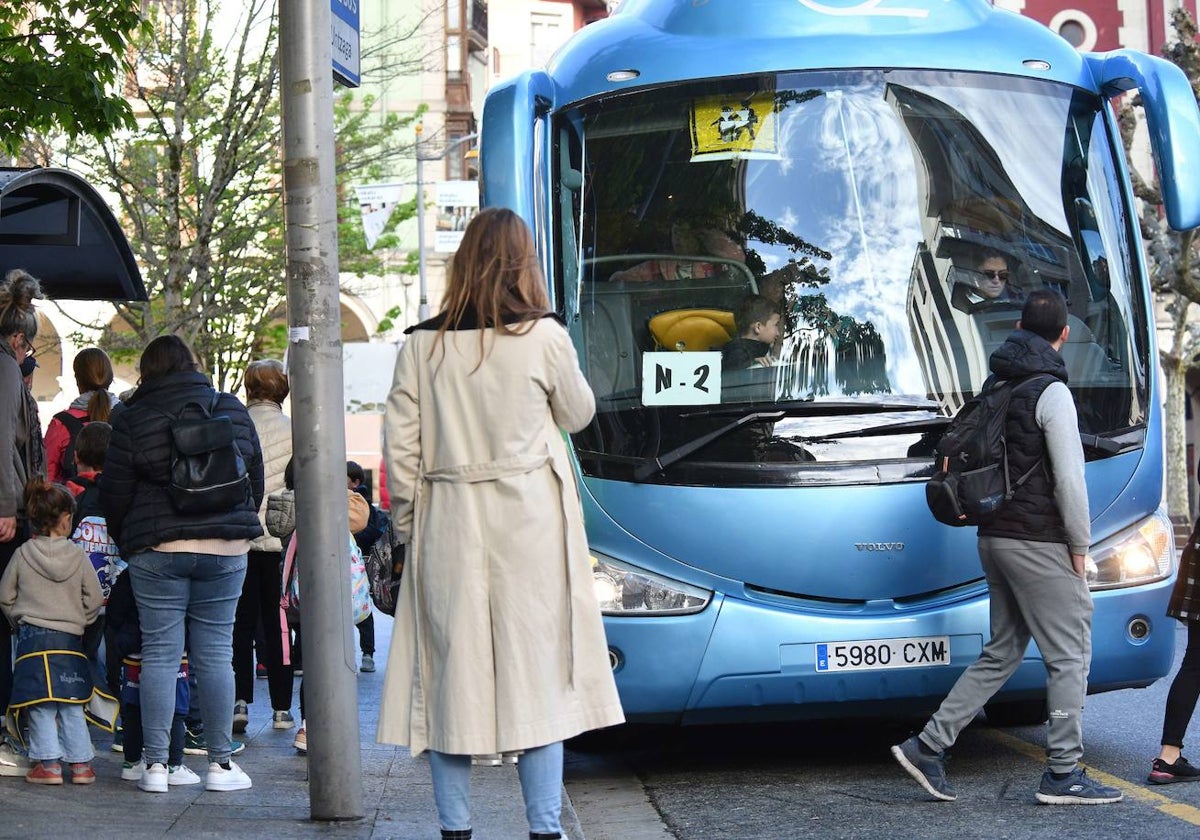 Familiares acompañan a sus hijos a coger un autobús escolar.