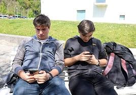 Dos jóvenes utilizan el teléfono móvil.