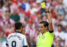 Munuera Montero muestra la tarjeta amarilla a Carlos Fernández por la mano que cometió en el partido entre el Atlético de Madrid y la Real Sociedad.