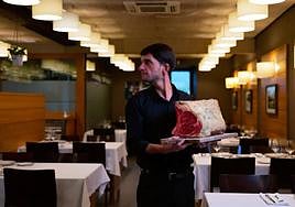 Álvaro sostiene una gran pieza de chuleta de vaca camino de la parrilla del Zubiondo.