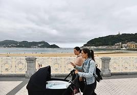 Una mujer pasea con un carrito de bebé por el paseo de La Concha