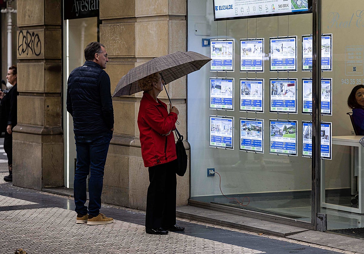 Dos personas observan los anuncios de una inmobiliaria.