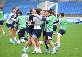 Los jugadores de la Real Sociedad se abrazan en un juego del entrenamiento de este martes en Zubieta, con André Silva detrás.