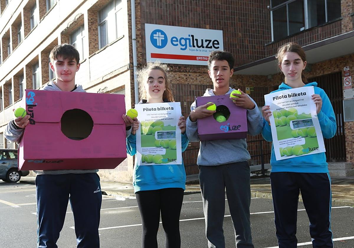Inclusión. Cuatro alumnos de 2º DBH del cole-gio Egiluze con cajas para recolectar pelotas y los carteles de la iniciativa.