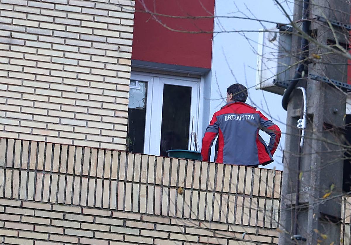 Un ertzaina inspecciona el cristal de la ventana por donde entró el disparo en la casa de la vecina de Deba.