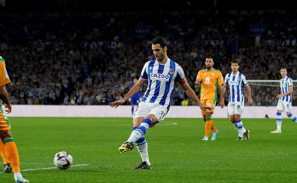 Mikel Merino busca un pase con la zurda en el partido contra el Betis en Anoeta, con Martin Zubimendi y Jon Pacheco siguiendo la jugada. 