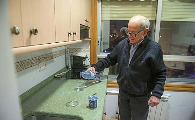 Antonio Iriarte, en la cocina de su casa, se sirve un vaso de agua. 