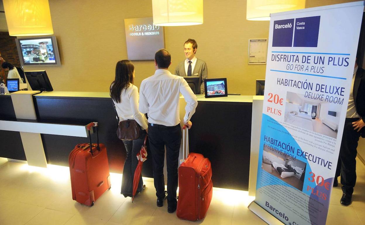 Una pareja espera en la recepción de un hotel para alojarse. 