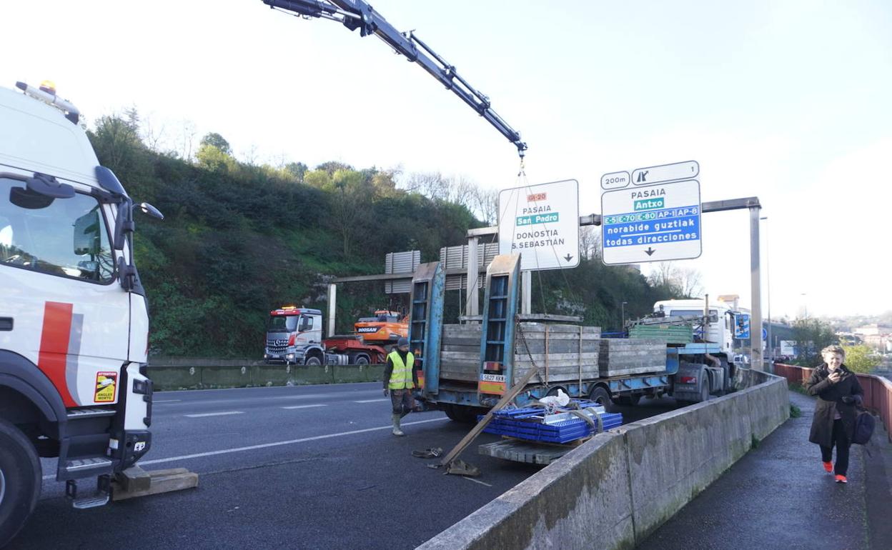 Una grúa retira las piezas metálicas que ha perdido el camión. 