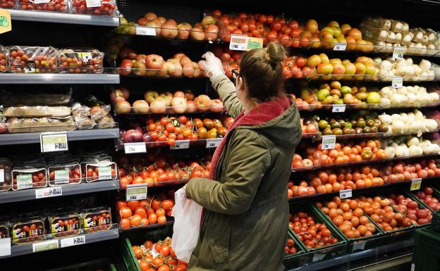 Una mujer escoge verduras en un supermercado.