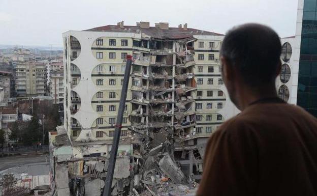 A man observes the search operations among the remains of a building in Diyarbakir (Turkey)