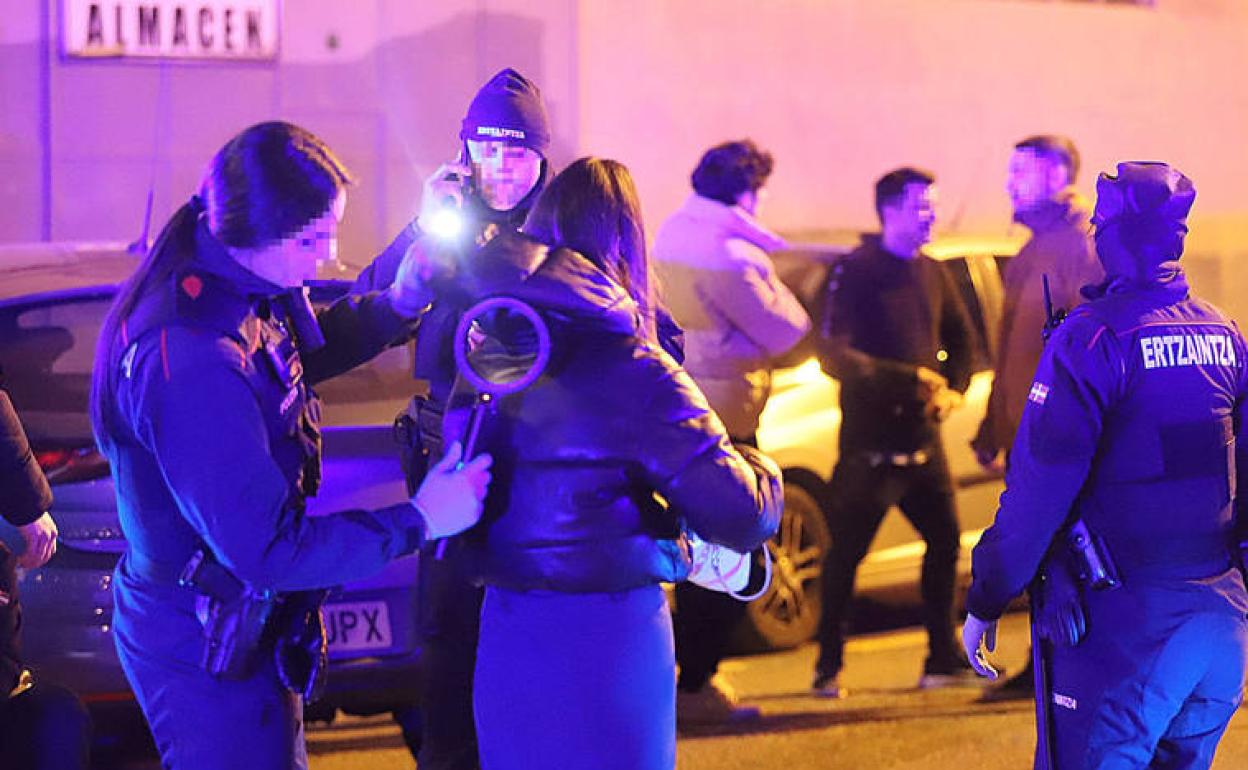 Agentes de la Ertzaintza cachean a jovenes a las puertas de una discoteca en Zorrozaurre, Bilbao 