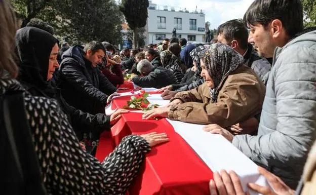 Relatives and friends cry over the coffins of those who died in the earthquakes