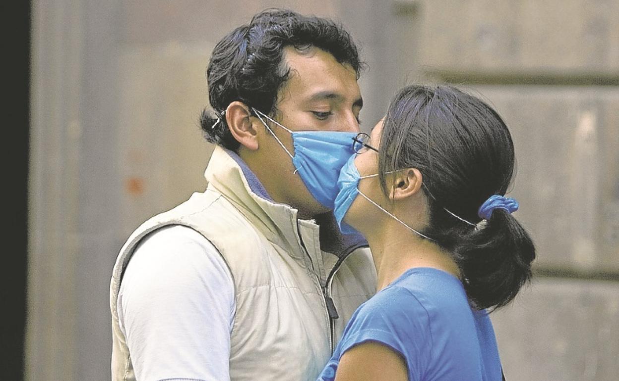 Una pareja muestra su amor a través de sus mascarillas. 