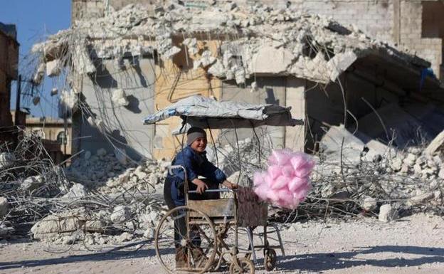A boy sells cotton candy next to the ruins of the Syrian town of Atarib.