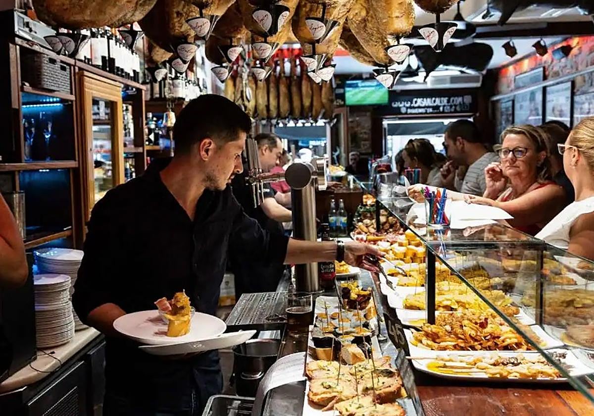 Un camarero atiende en un bar lleno de clientes.
