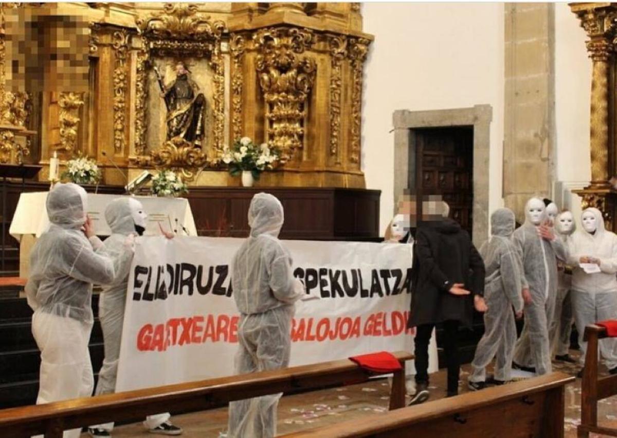 Imagen secundaria 1 - Miembros de la Gazte Asanblada de Zestoa entran enmascarados en la iglesia durante la misa mayor