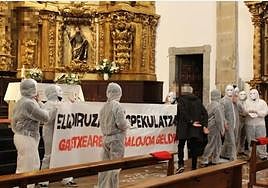 Una pancarta frente al altar donde se puede leer 'Iglesia avariciosa, especuladora!'.
