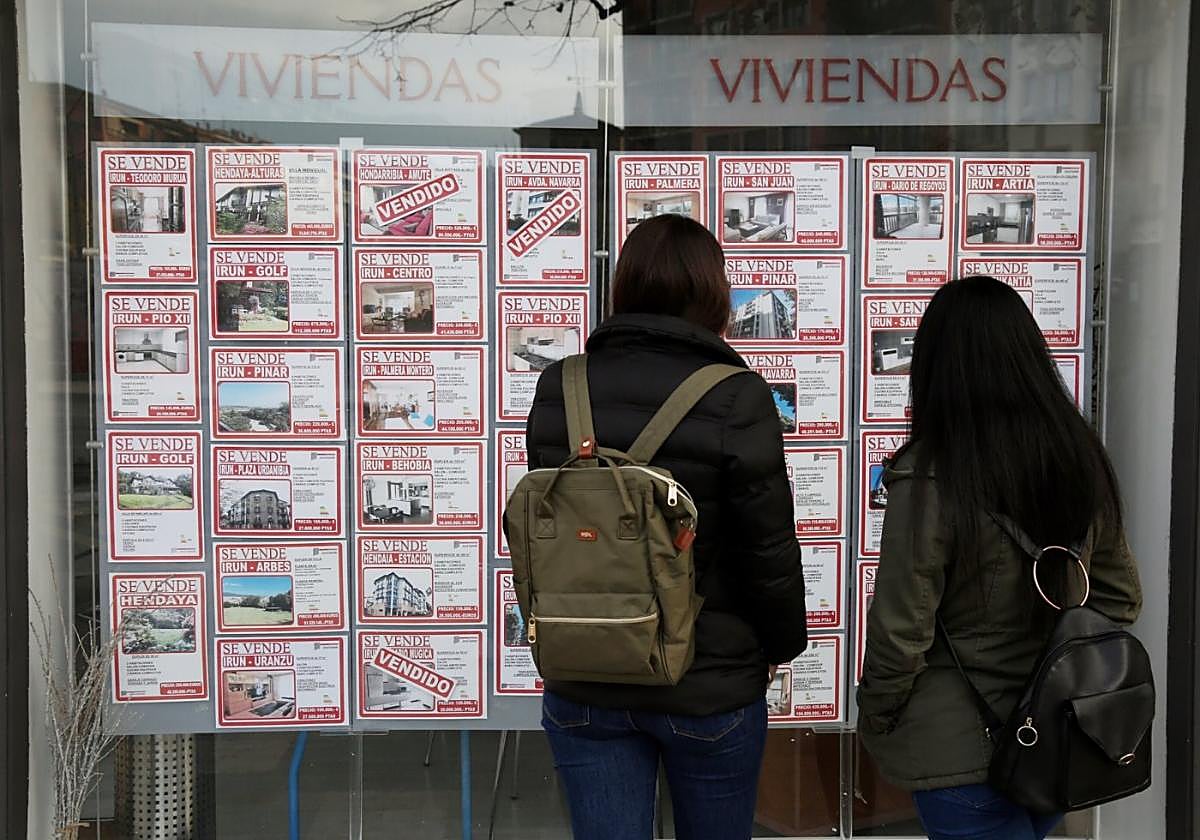 Dos clientas analizan los diferentes anuncios del escaparate de una inmobiliaria en Irun.