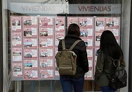 Dos clientas analizan los diferentes anuncios del escaparate de una inmobiliaria en Irun.