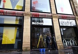 Dos trabajadores del McDonalds de La Bretxa limpian la entrada del local, que ha sufrido un lanzamiento de pintura.