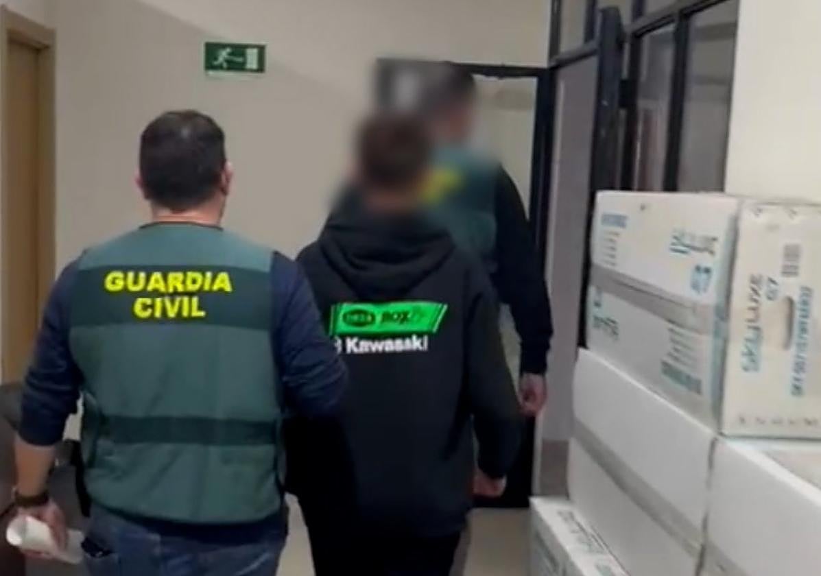 Dos agentes acompañan a un menor detenido a través de dependencias policiales.