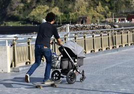 Un padre pasea a su bebé en San Sebastián montado en un monopatín.