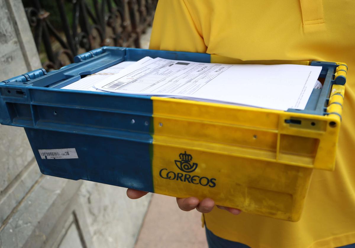 Un empleado de Correos procede a entregar la correspondencia.