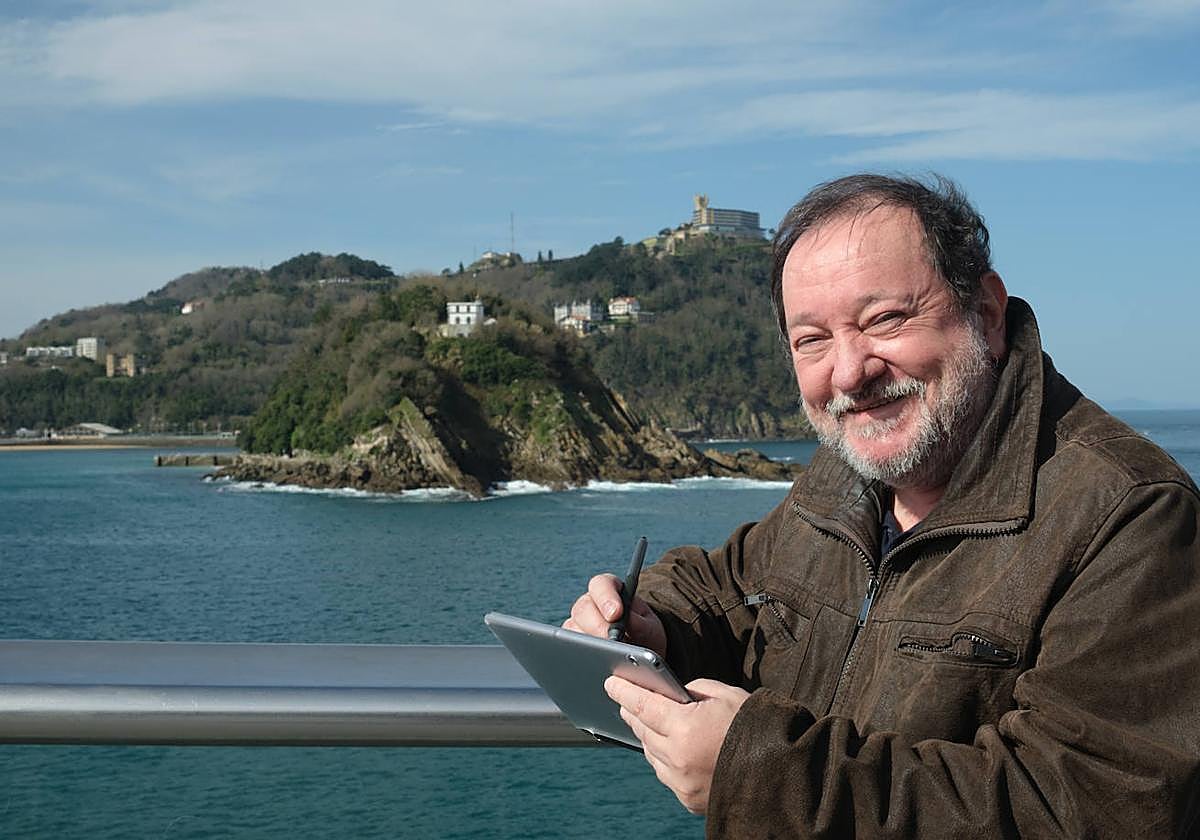 Adolfo Luzuriaga dibuja en su tablet con la isla al fondo.