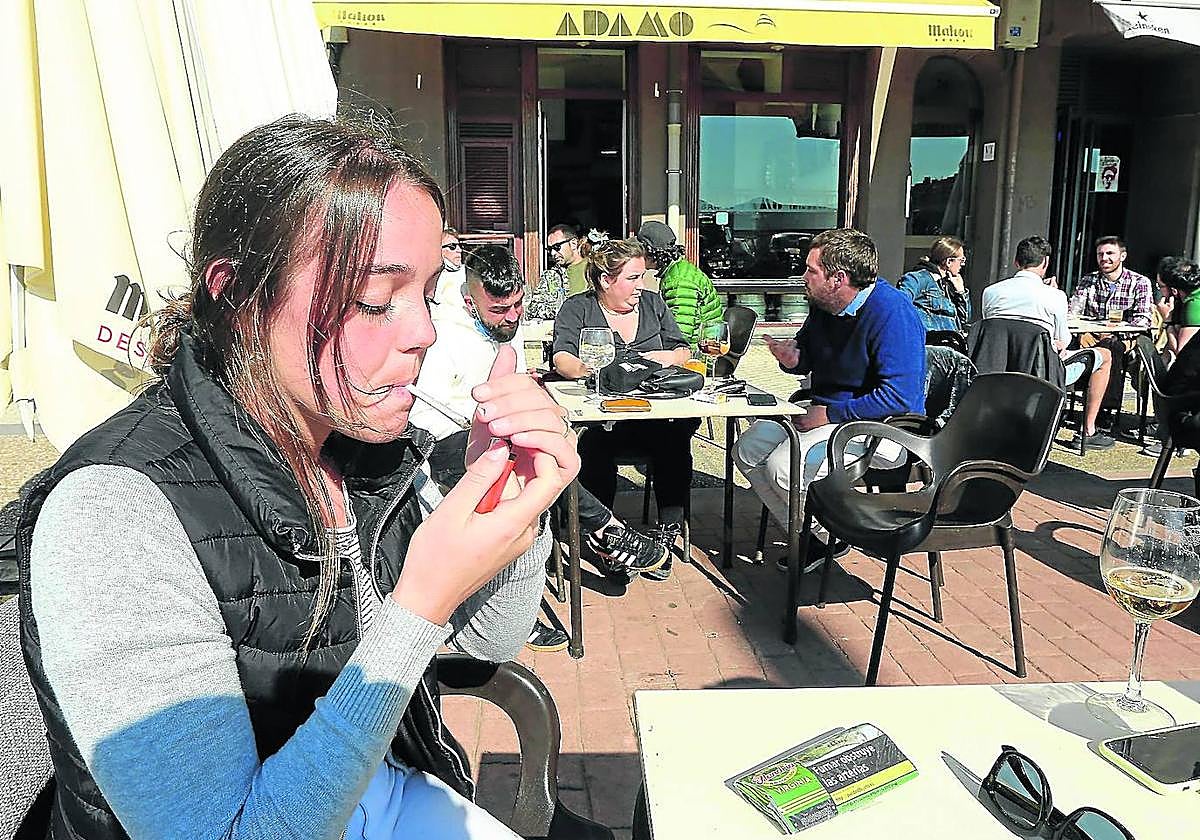 Una joven se enciende un cigarrillo en la terraza de un bar de Donostia.