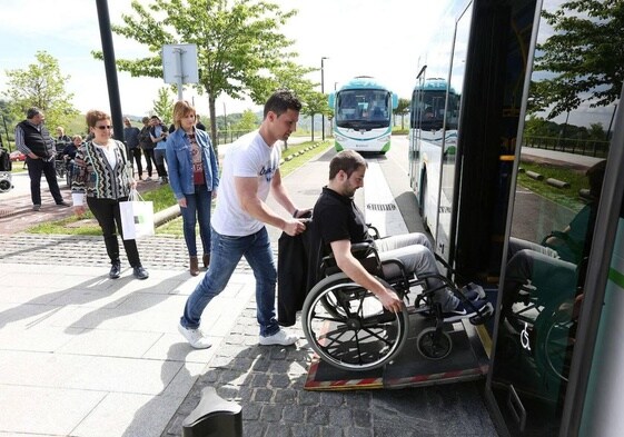 Una persona ayuda a otra con silla de ruedas a subir a un autobús.